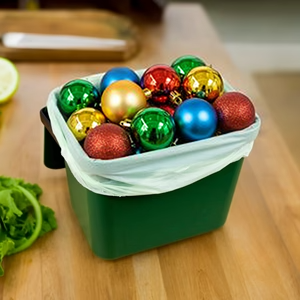 Green plastic kitchen caddy on busy kitchen worktop - the caddy is filled with an array of colourful Christmas baubles