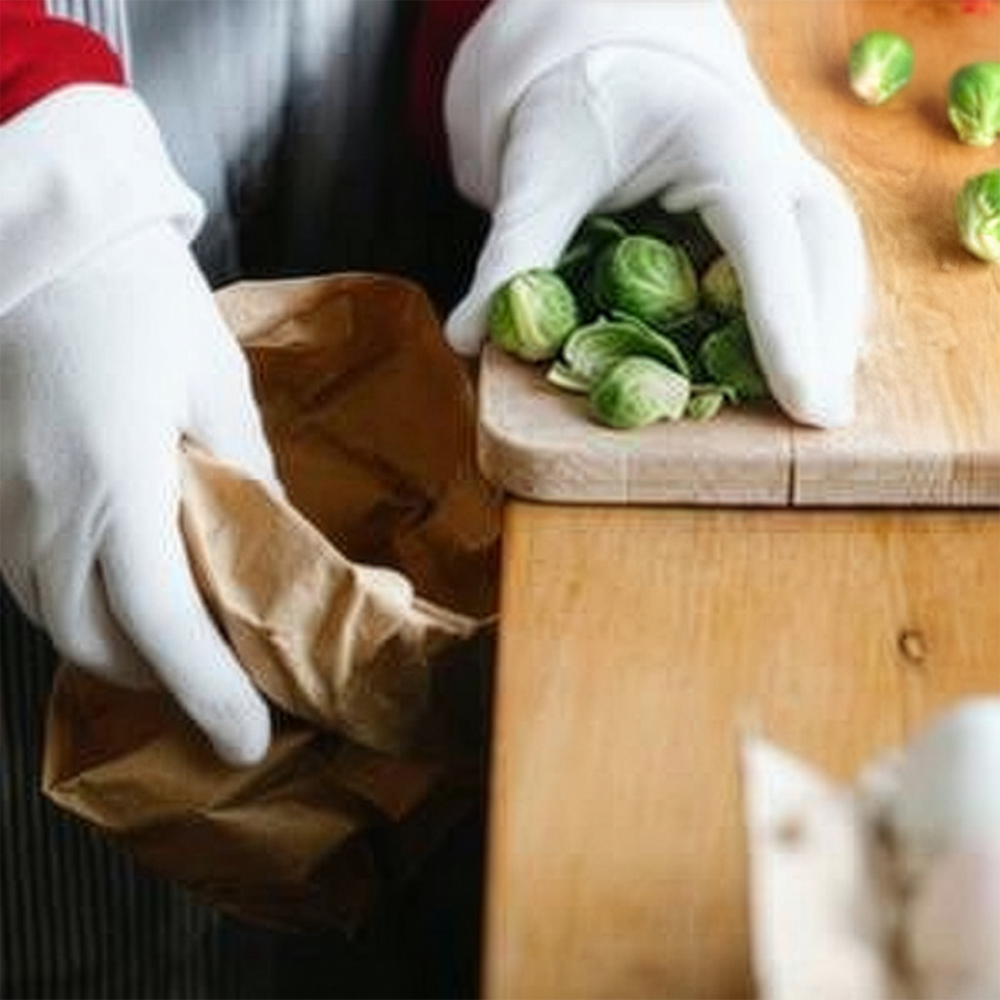 Chopped peppers being scraped into brown paper bag for kitchen food waste