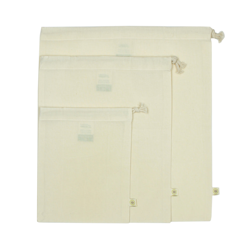 Set of three cream drawstring cotton produce bags in small, medium and large sizes, laid flat on white background