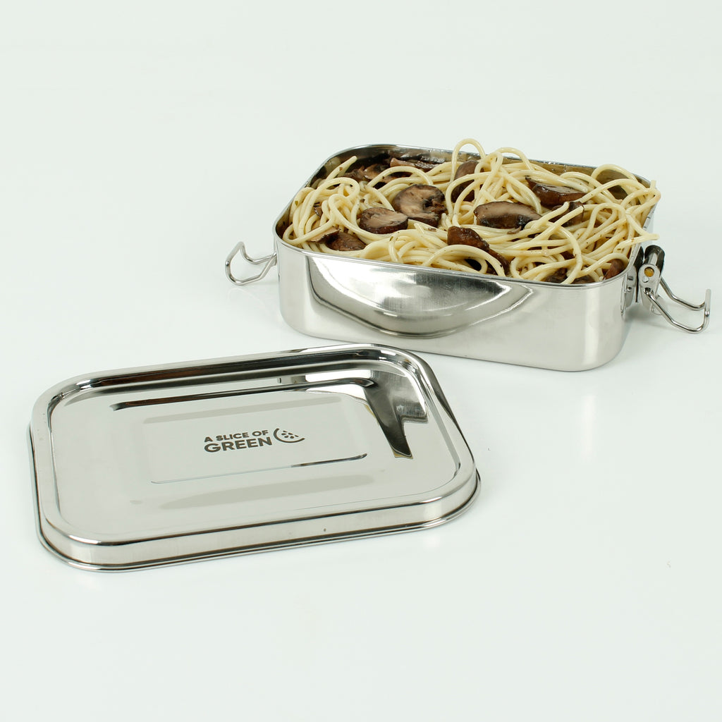 Open stainless steel lunch box filled with spaghetti and mushrooms, with branded lid placed beside on a clean white surface