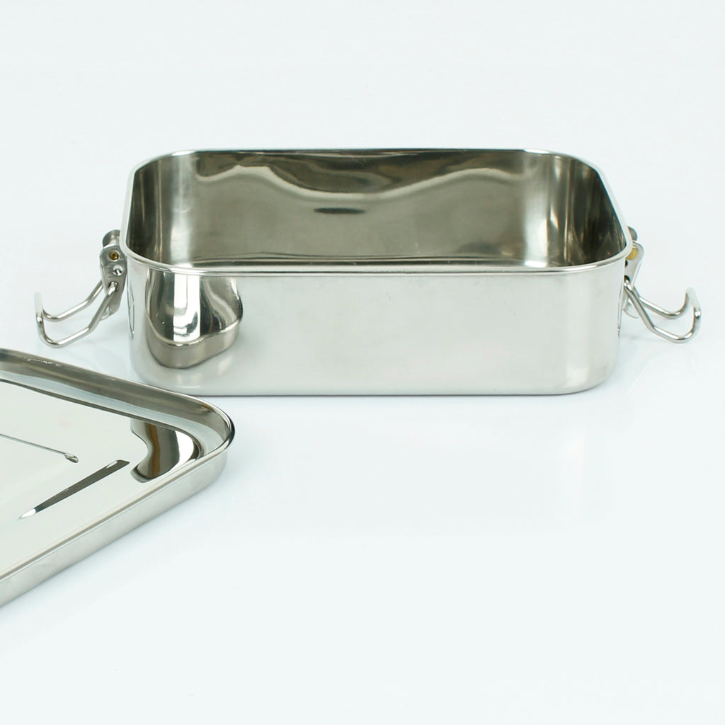 Empty stainless steel lunch box with open lid beside it, showing inner finish and side clasps against a plain white background