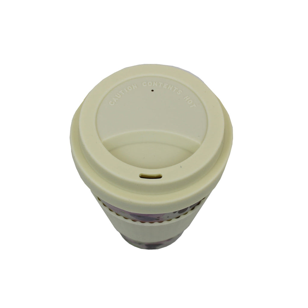 Reusable bamboo travel cup with cream lid viewed from above, lid marked “caution contents hot”