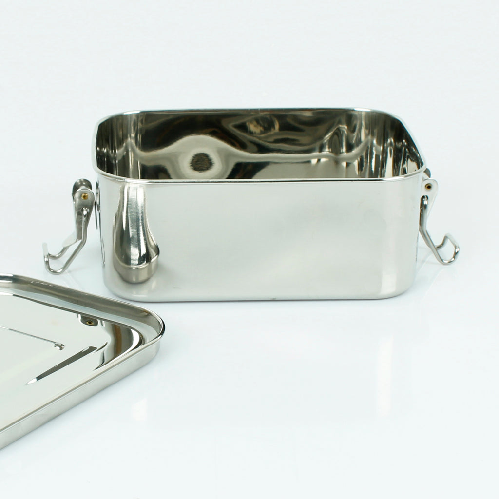 Empty stainless steel lunch box with open lid and side clasps, placed on a clean white surface
