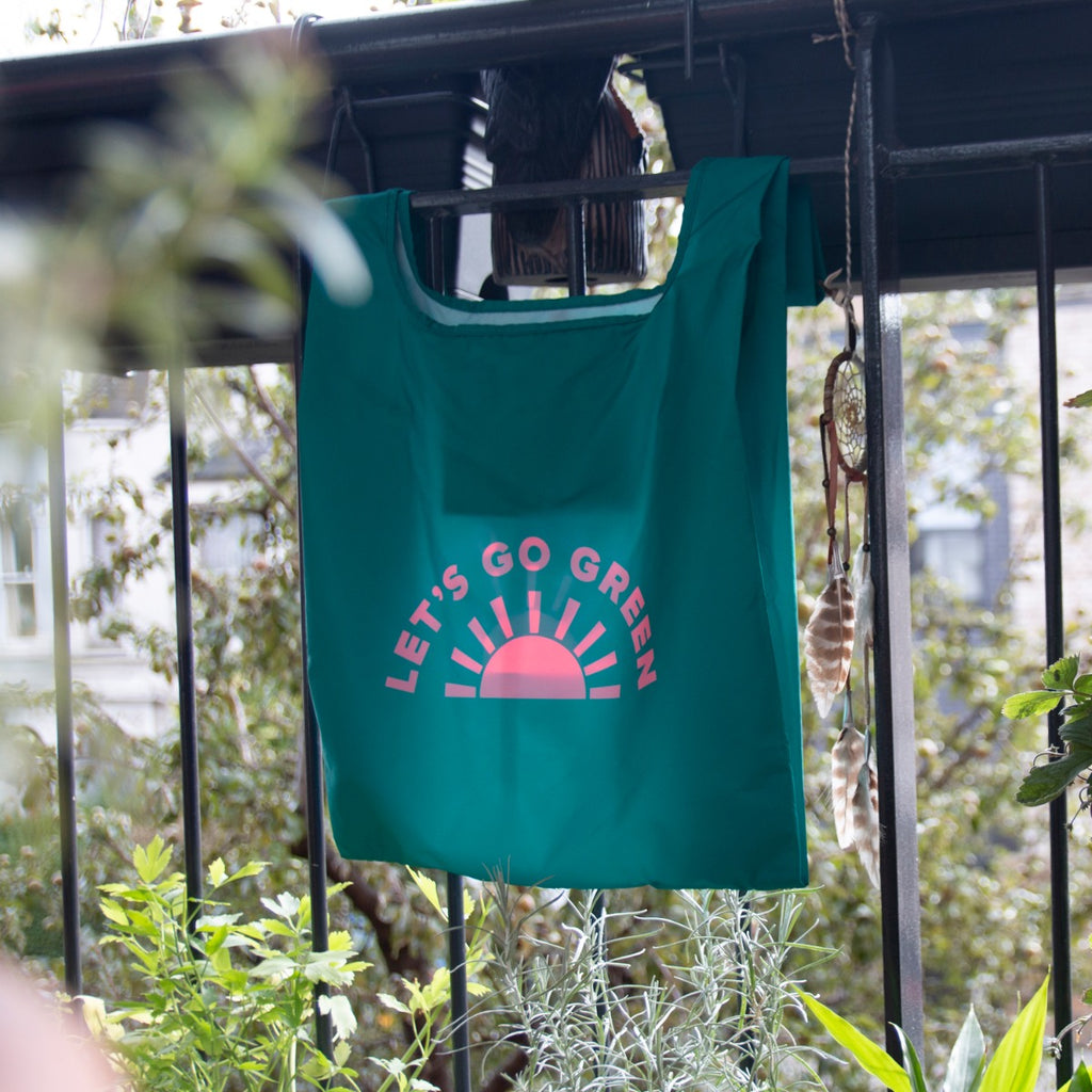 Open reusable grocery bag with coral text and sun emblem
