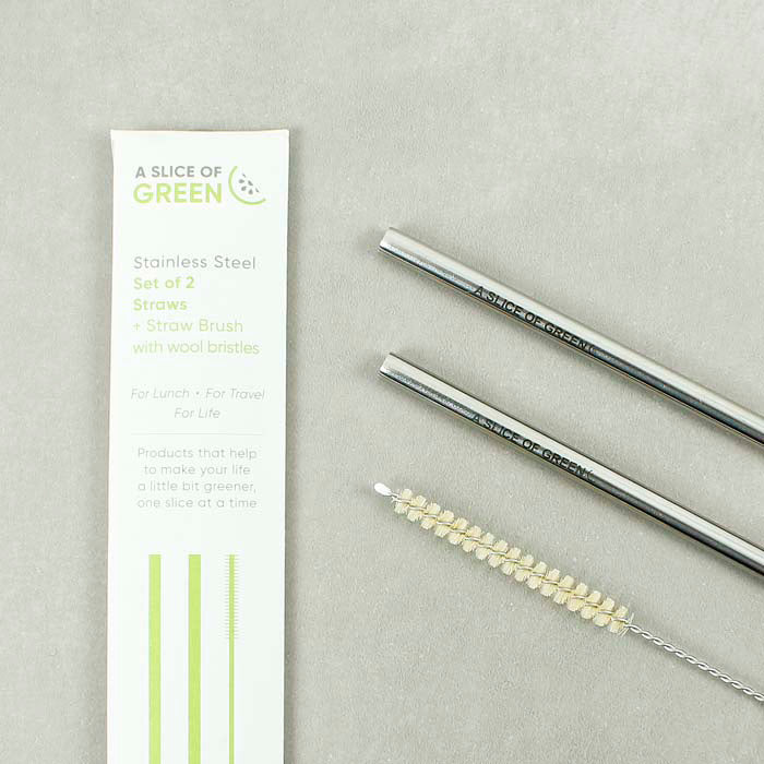 Close-up of A Slice of Green stainless steel straws set with cleaning brush and branded paper sleeve on a neutral background