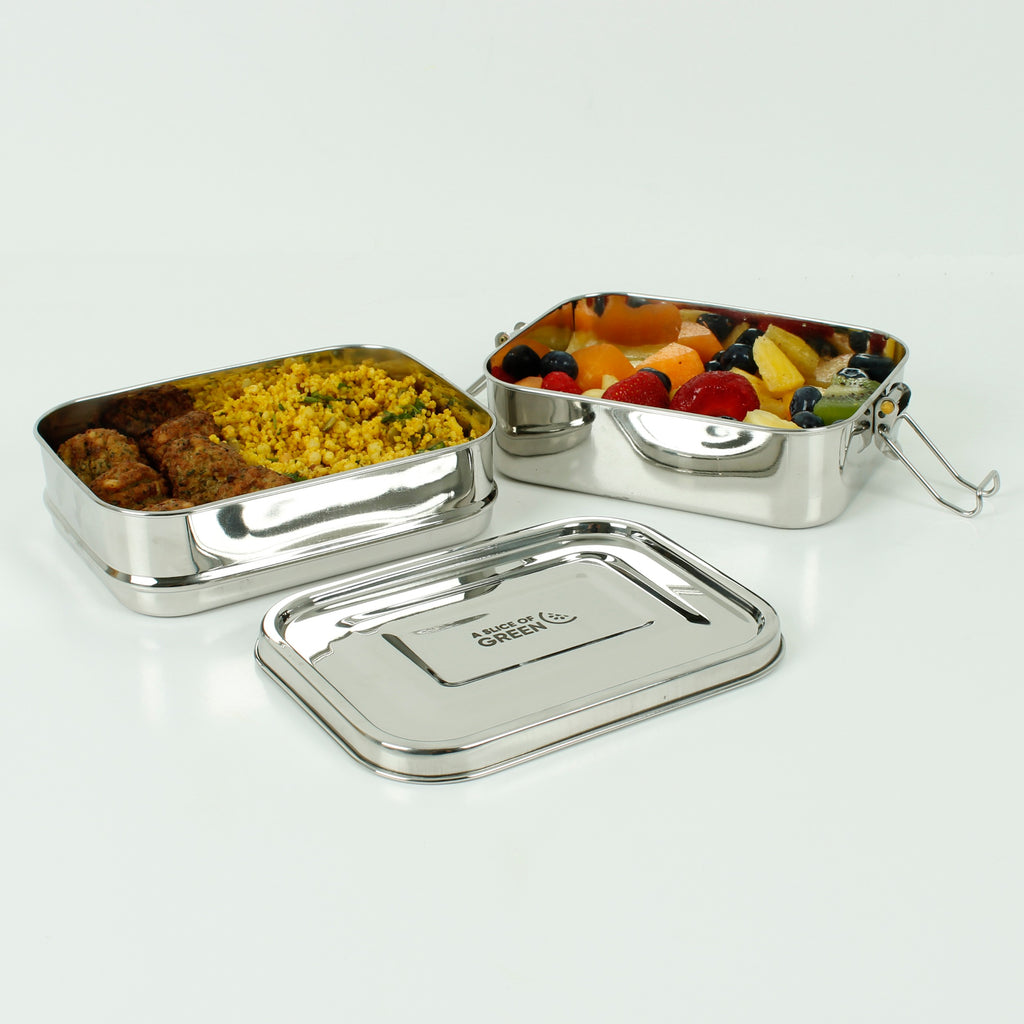 A pair of stainless steel food containers, containing cous-cous, falafel, & fruit salad